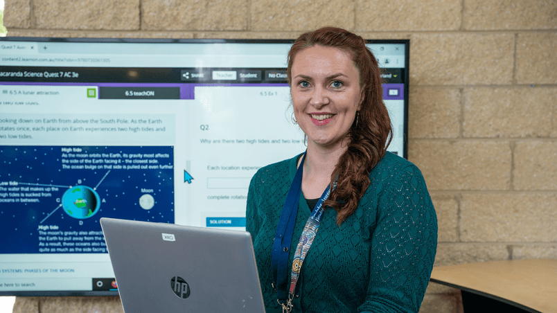 Woman with laptop and large screen in background