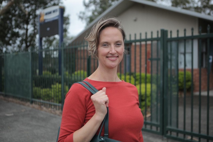Woman standing in front of school in red shirt with handbag