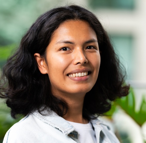Student smiling at camera with greenery in background
