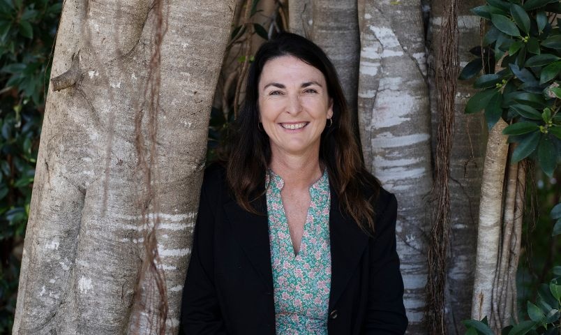 Women in black jacket standing in front of large tree
