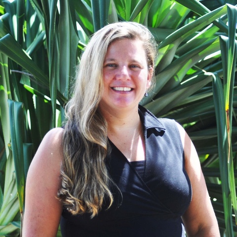 Blonde haired lady smiling with bushes in background