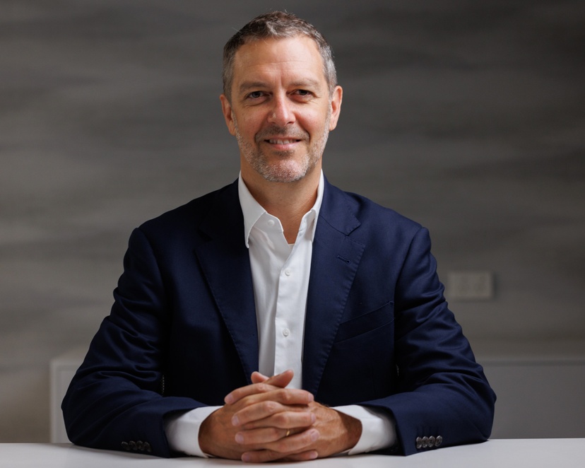 Man sitting at desk with hands folded in front of him