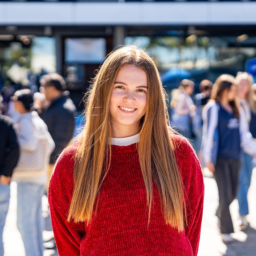 Student in red jumper smiling at the camera