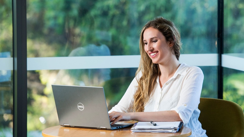 Woman working at laptop with forest in background