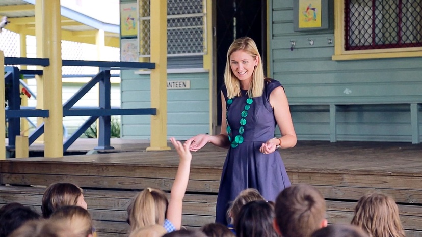 Lady talking to group of primary students at school