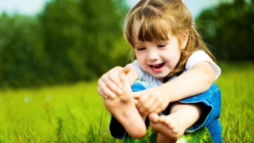 child playing with feet in the grass