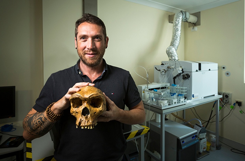Dr Renaud Joannes-Boyau in his lab holding a scull