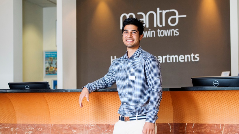 Hospitality and tourism graduate standing in front of concierge desk in modern accommodation setting