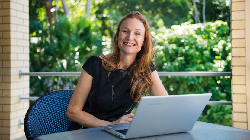 Woman sitting at a laptop, smiling at camera
