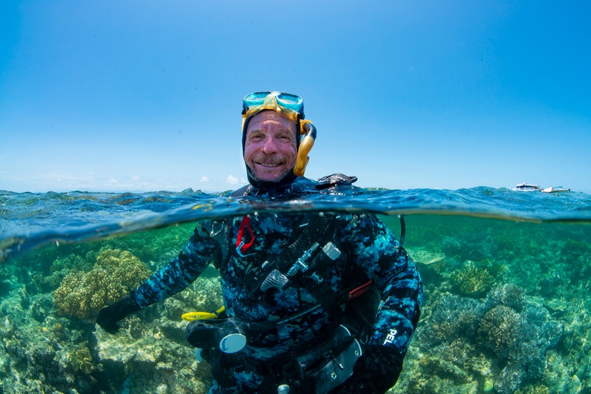 Scuba diver emerging from the ocean surrounded by coral reef