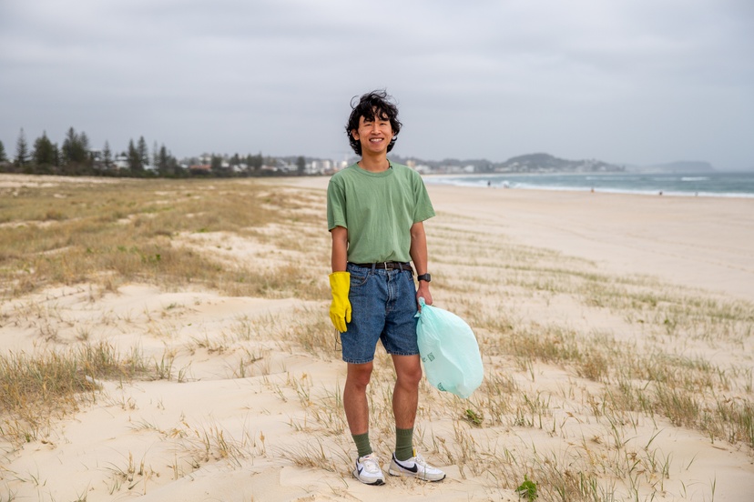 Johnny standing on beach with gloves and bag