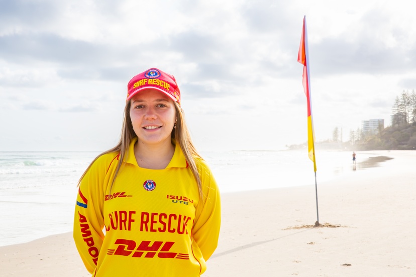 Student in surf lifesaving uniform at beach in front of red and yellow flag
