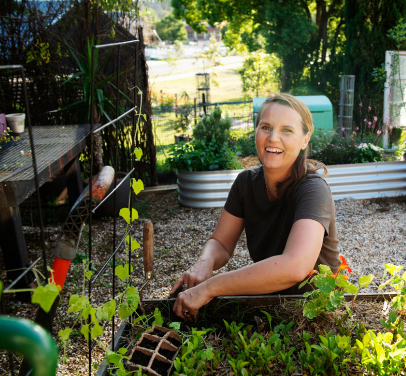 A woman kneels in a vegetable garden