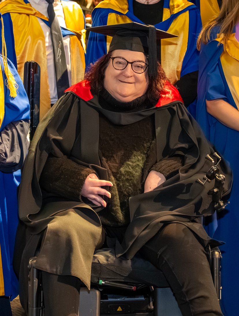Woman in robe and cap at graduation in a wheelchair