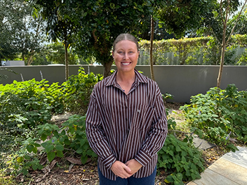 Headshot of woman in striped shirt in front of greenery
