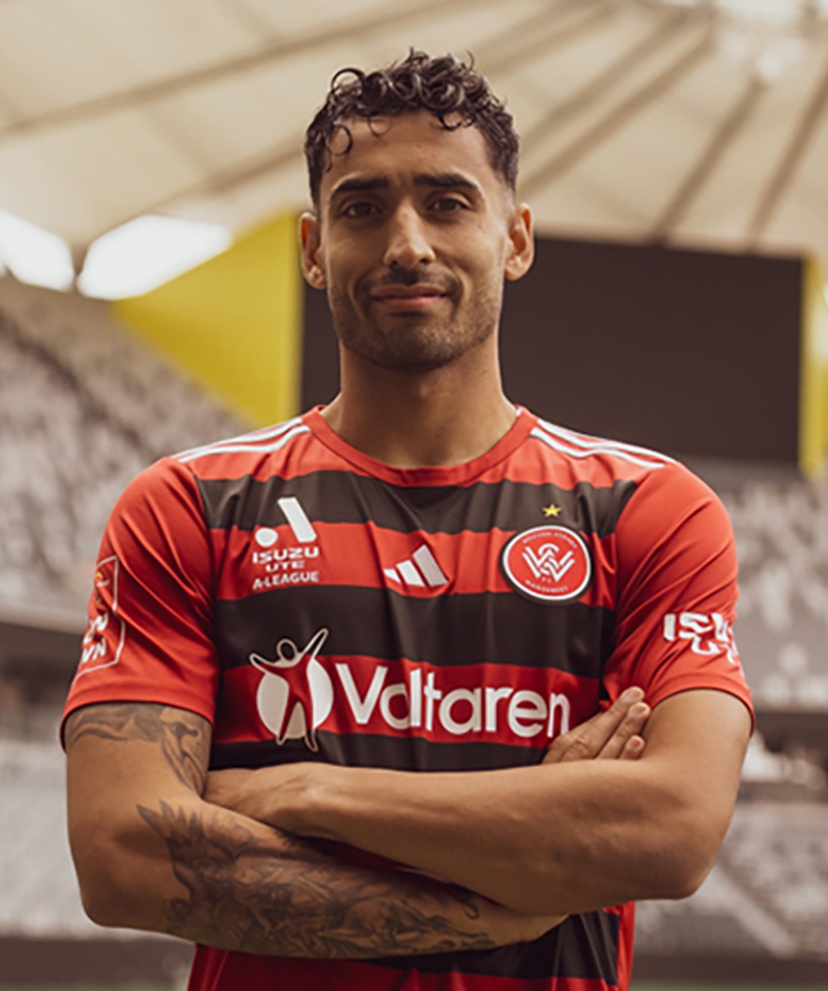 A man in a stadium wearing a sports jersey with his arms crossed