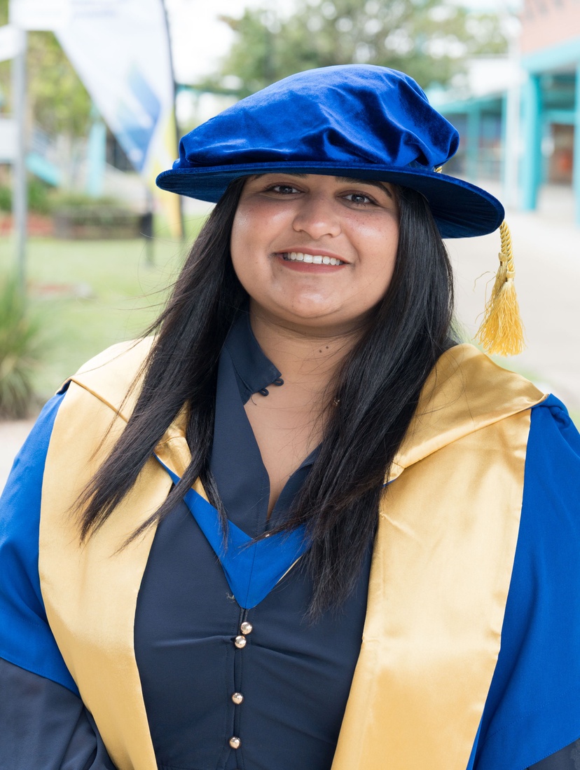Female smiling at camera in graduation robe and cap