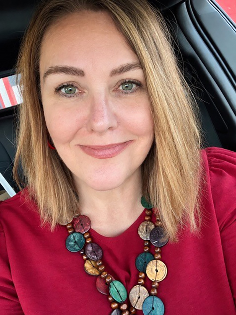 A woman wearing a red top and a stone necklace