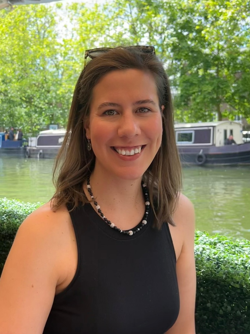 A woman wearing a black tie sitting in front of a pond