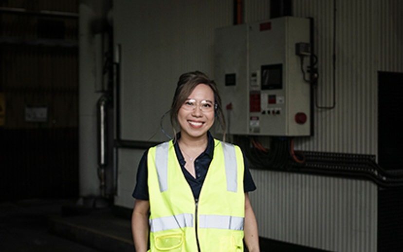 Woman smiling at camera in high vis vest and safety glasses