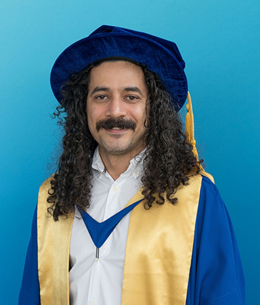 Man in graduation robe and cap with blue background