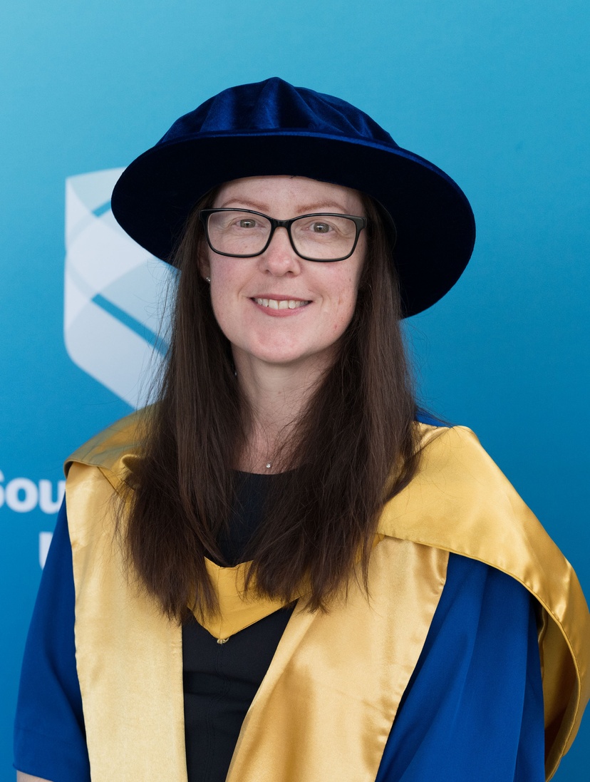 Female smiling at camera in graduation robe and cap