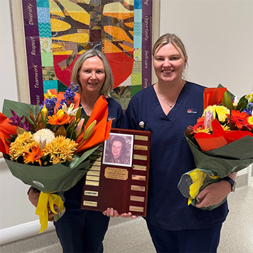 Two women holding awards and flowers