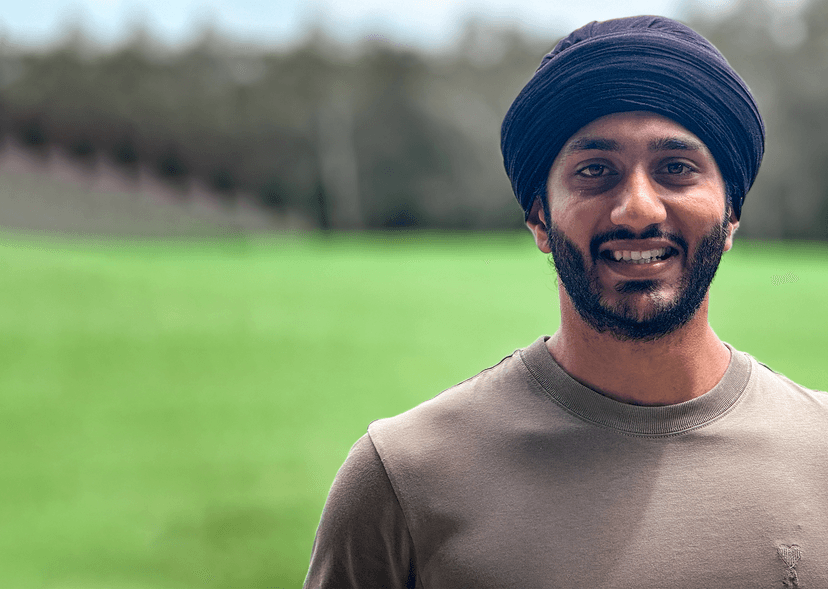 Gurpreet smiling at camera with blurred grassy field and trees in background