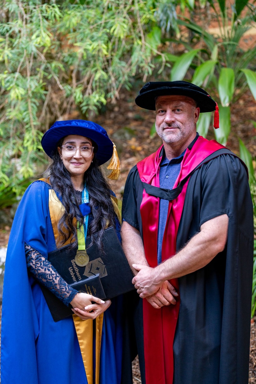 Female and male in graduation robes smiling at camera