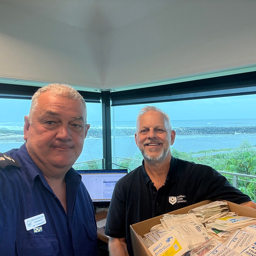 Jonathan Wilcock from Marine Rescue NSW receiving first aid supply donation from Michael Karkkainen, Workplace Health and Safety Advisor at Southern Cross University