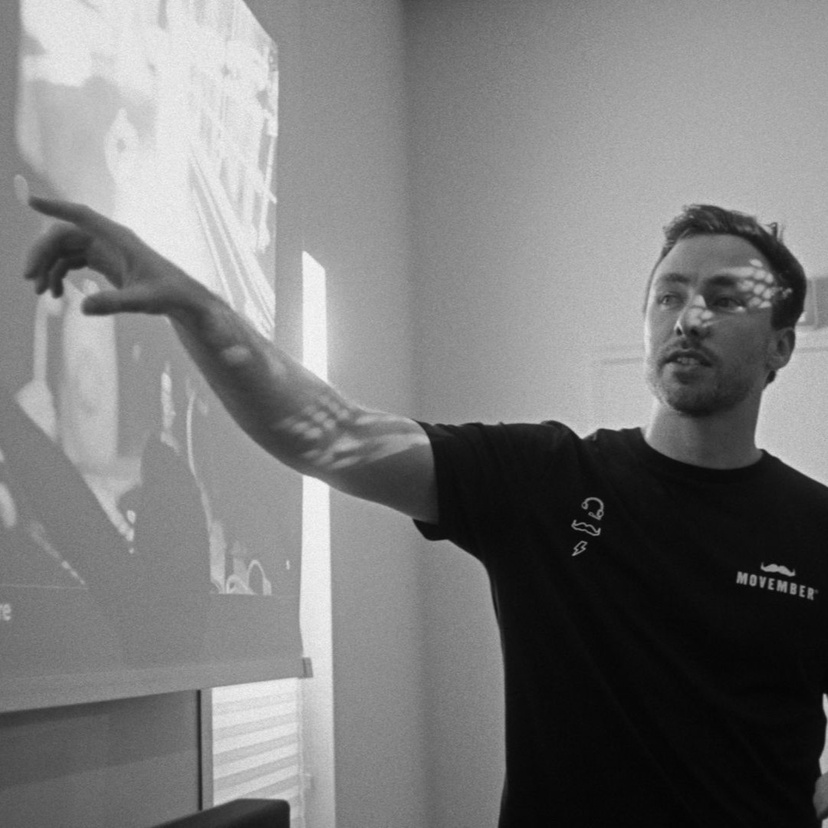 Black and white photo of man pointing at white board