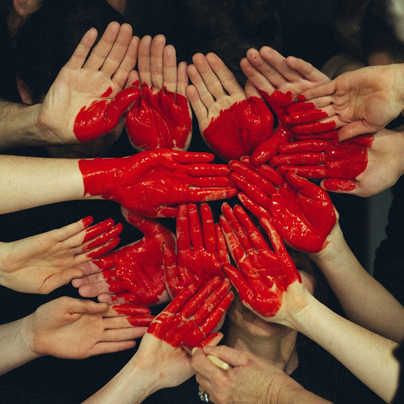 multiple hands overlapping with red painted heart on them