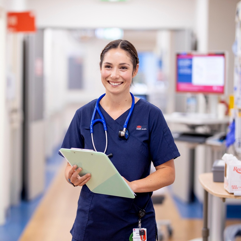 person standing and smiling at camera holding clip board