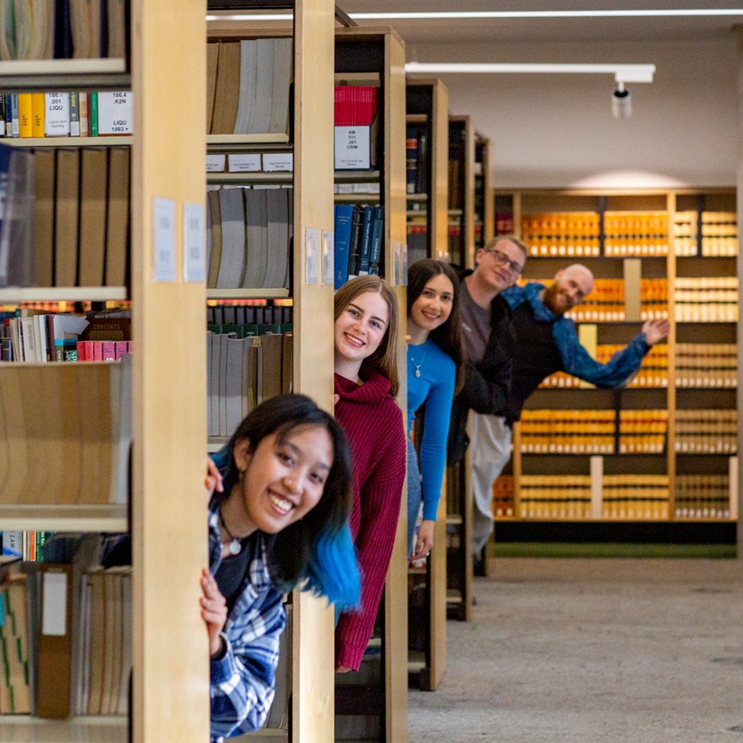 Group of student peeking out from bookshelves in the Learning Centre