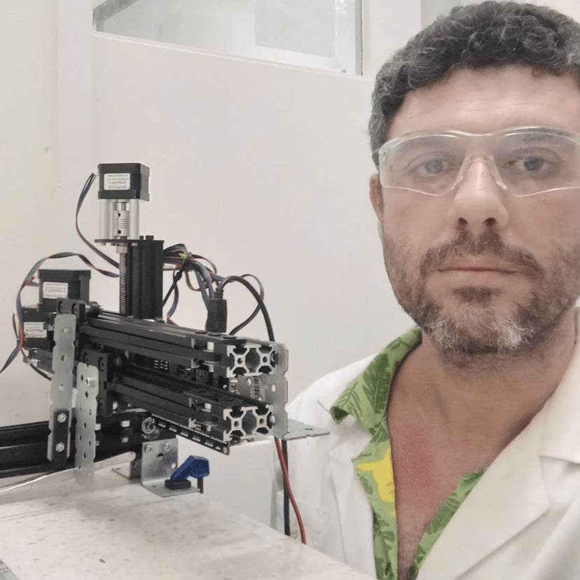 Man in white lab coat where protective glasses looking at camera