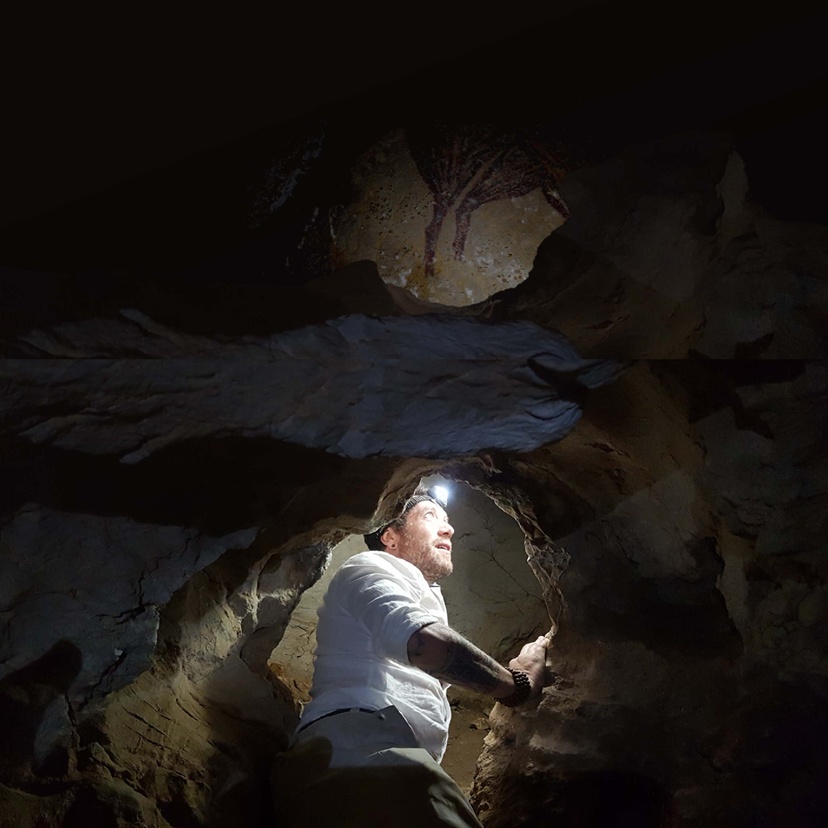 Man wearing head torch, climbing through dark cave