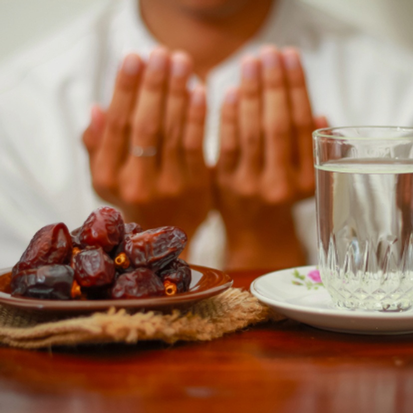 Fast breaking meal or iftar dish with muslim man hands praying to Allah