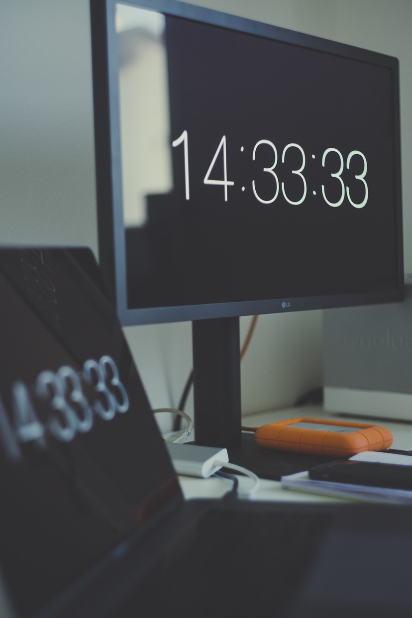 Laptop and additional screen on desk with time displayed