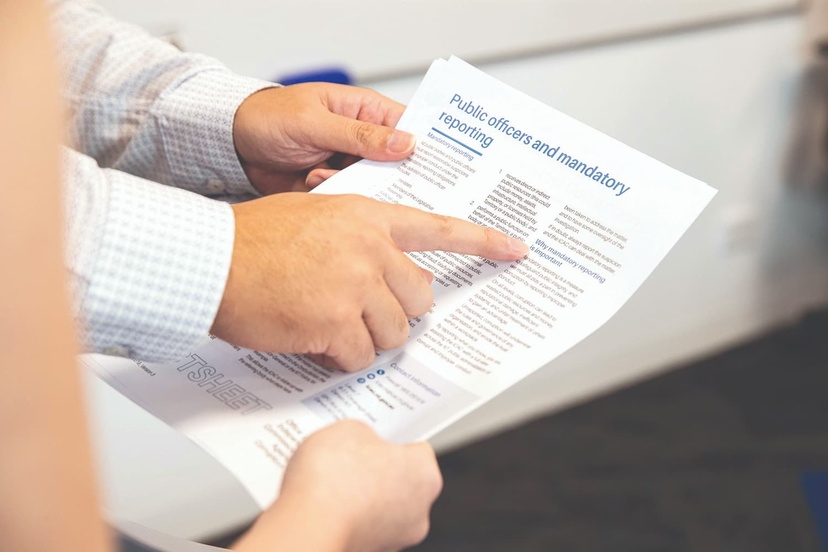 A reporting document being held between two people and pointed at
