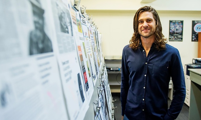 Nick Paton, Bachelor of Indigenous Knowledge student stands to the side of a series of historical postwer presentations that are about generational knowledge