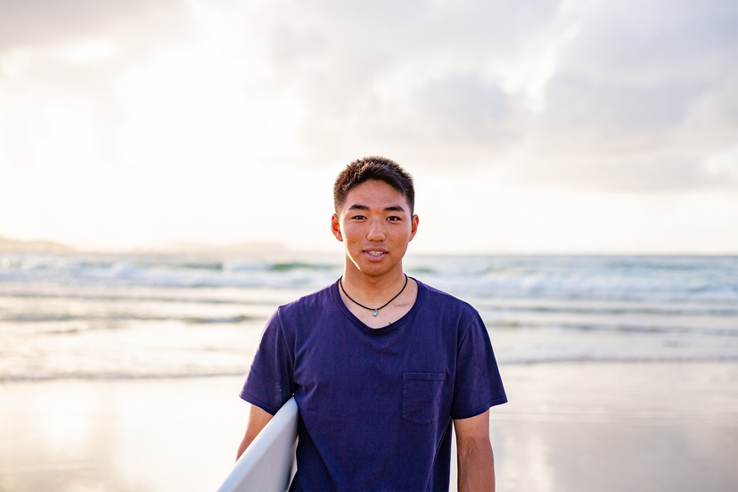 Student holding a surfboard at the beach