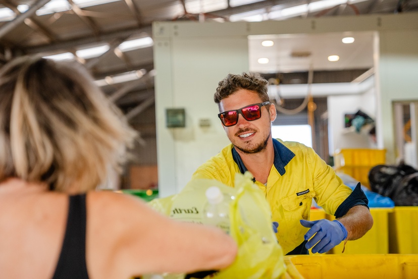 A man wearing high visibility work wear sorting through plastic