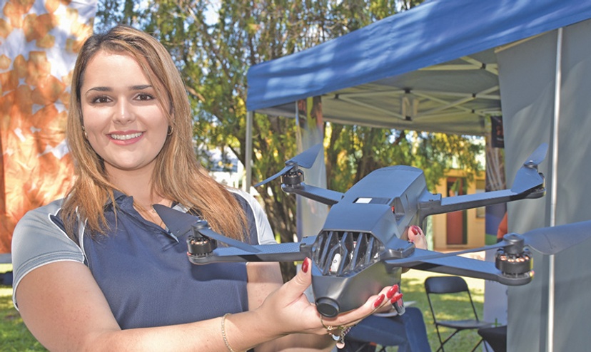 Dayna Scalpin, SCU graduare holds a drone outside in front of a tent
