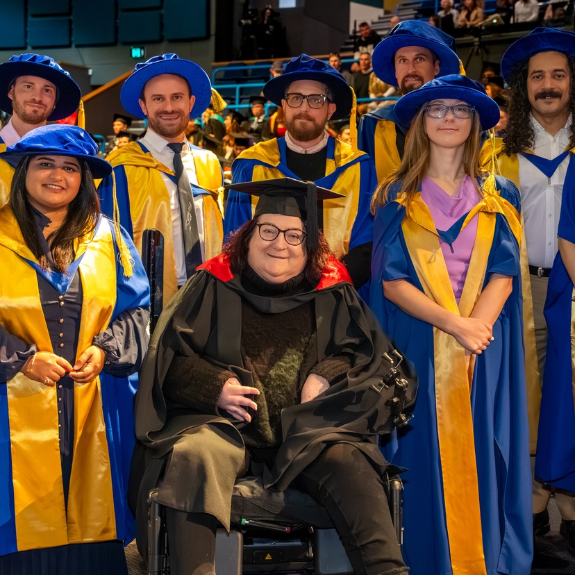 Graduates in robs and caps at graduation ceremony smiling