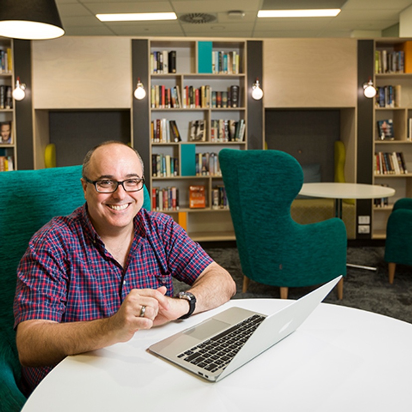 A man sitting at a desk with laptop in a library