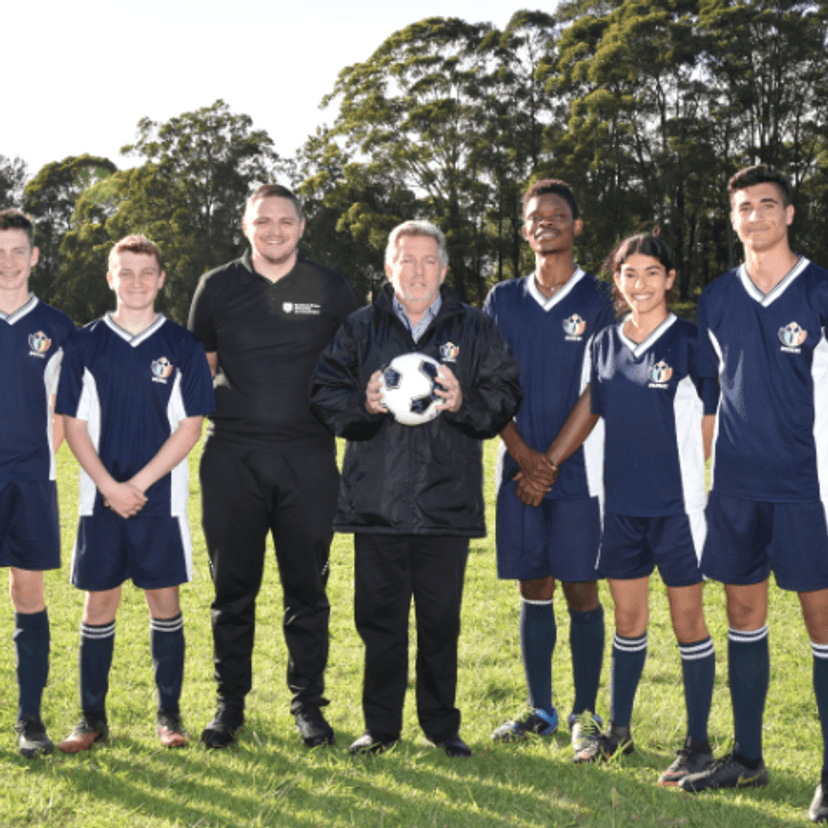 A group of young soccer players standing alongside two adults