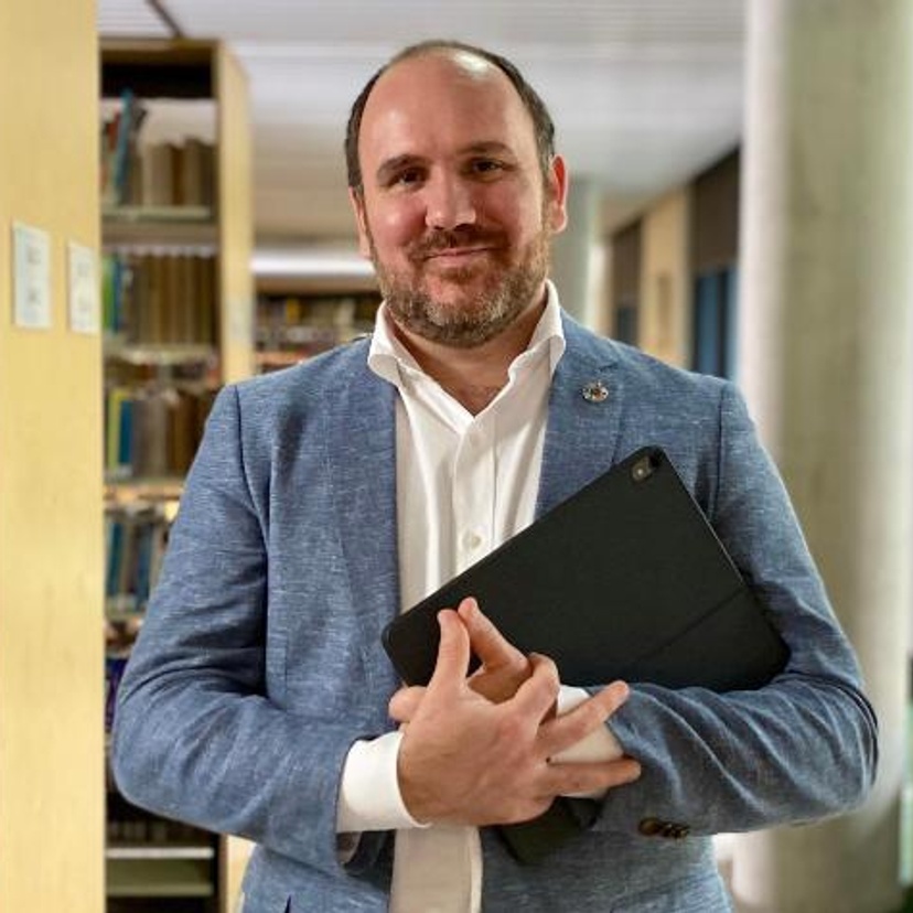 Man holding laptop in a library