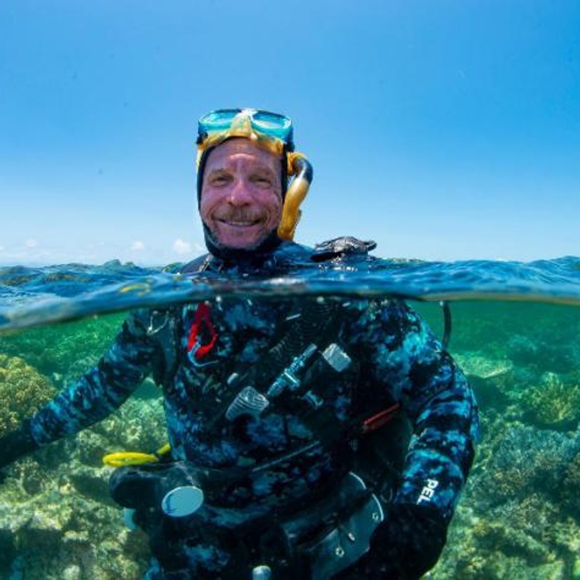 Scuba diver emerging from the ocean surrounded by coral reef