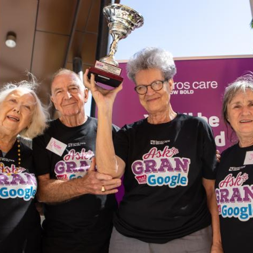 A group of senior citizens holding a winner's trophy.