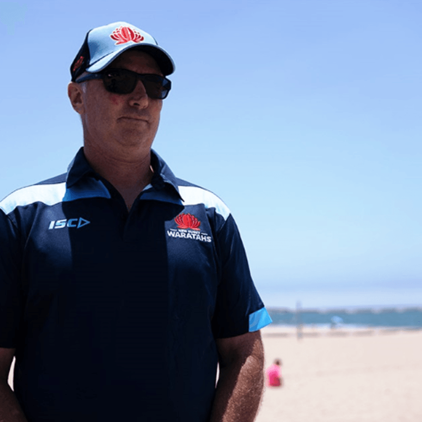 Man wearing NSW Waratahs polo and hat at a beach